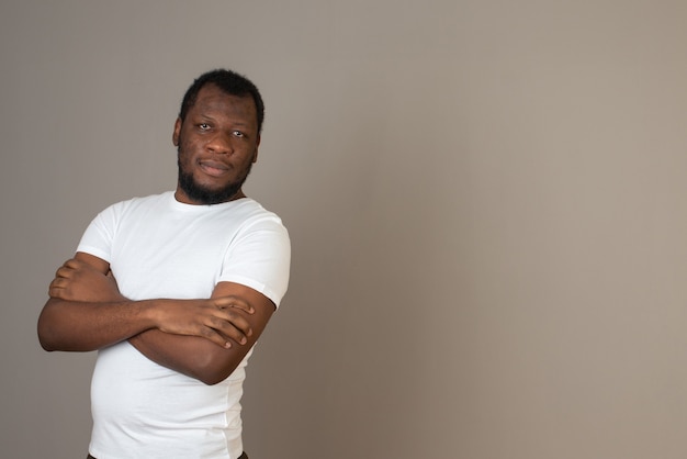 man holding arms folded ,standing in front of the grey wall