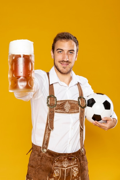 Foto gratuita uomo che tiene una palla e una pinta di birra