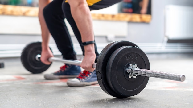 A man holding a barbell on the floor in the gym