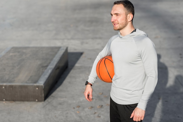 Foto gratuita uomo che tiene una pallacanestro e distogliere lo sguardo