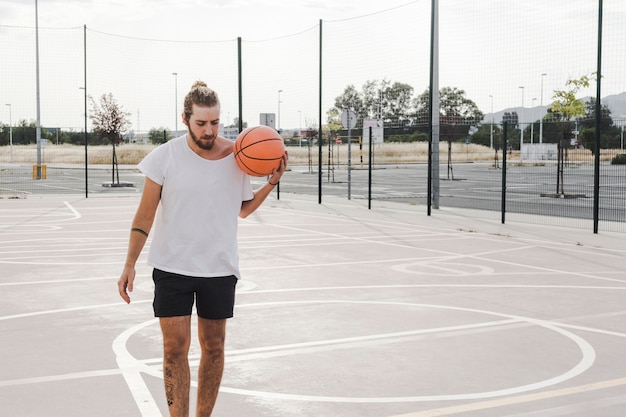 Free photo man holding basketball in outdoor court