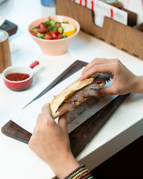 Man holding beef kebab in bread at the cafe