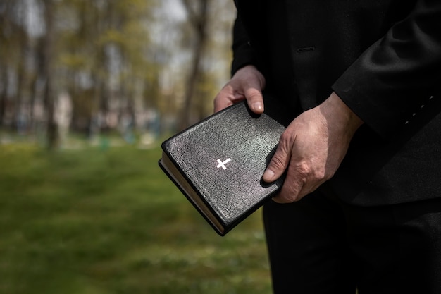 Free photo man holding bible while at the cemetery with copy space