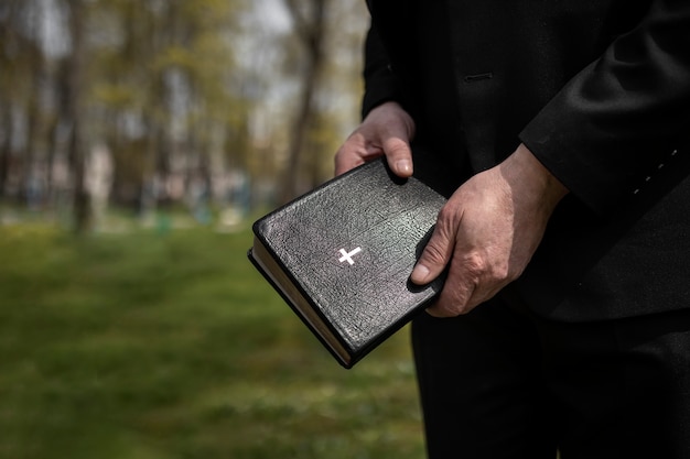 Man holding bible while at the cemetery with copy space