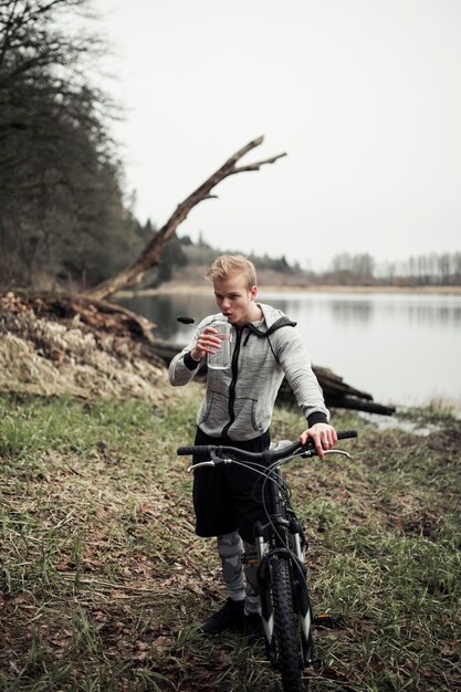 Man holding bicycle drinking water from bottle