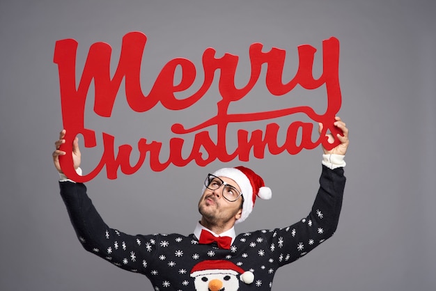 Foto gratuita uomo che tiene un grande cartello che dice buon natale