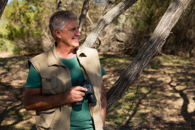 Man holding binocular at forest