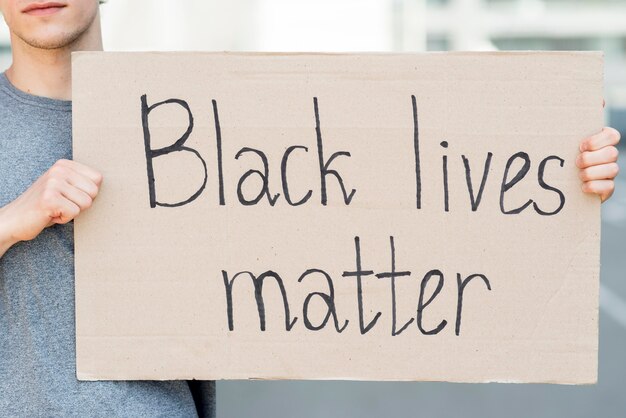 Man holding black lives matter quote on cardboard