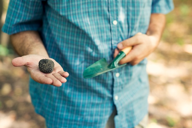 Man holding black truffle with thumb up in nature