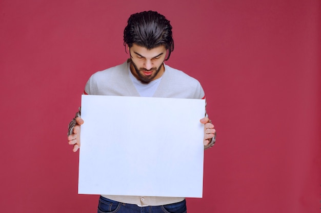 Free photo man holding a blank idea board and making presentation.