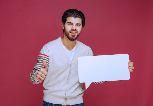 空白のアイデアボードを持って親指を立てる男。