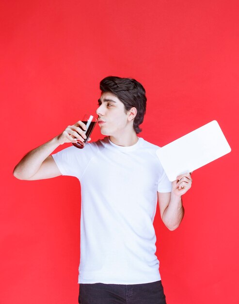 Man holding a blank paper and drinking a glass of juice. 