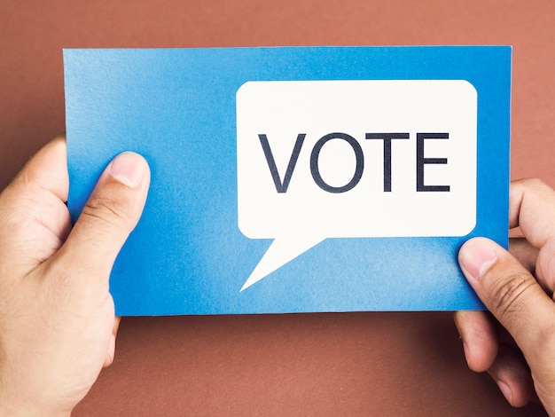 Man holding a blue card with a voting speech balloon