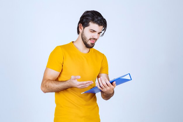 Man holding a blue folder and checking the reports.