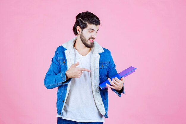 Man holding a blue folder and pointing at it