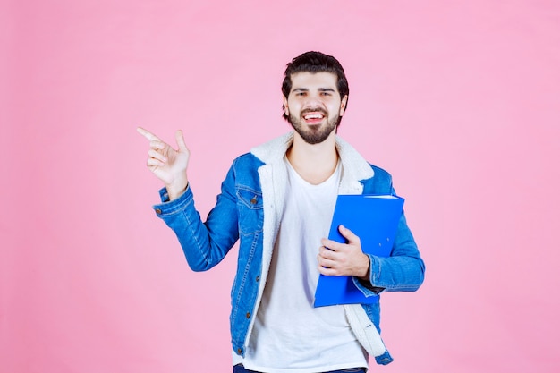 Man holding a blue folder and pointing to the left side