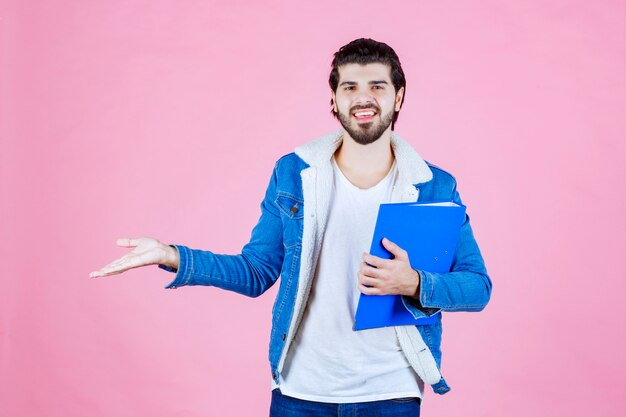 青いフォルダーを持って左側を指している男