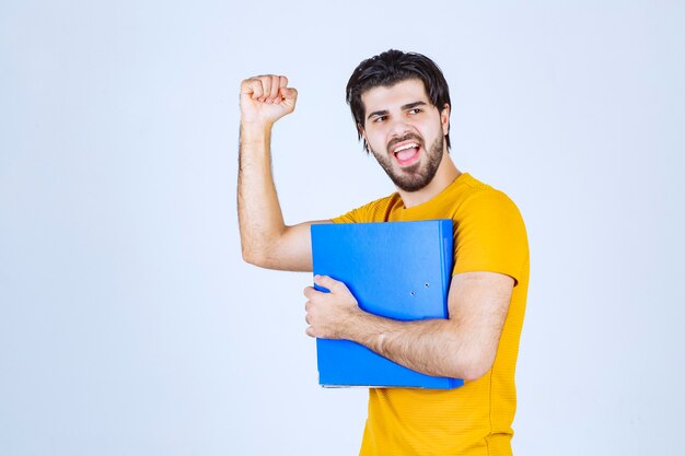 Man holding a blue folder and showing his fist.