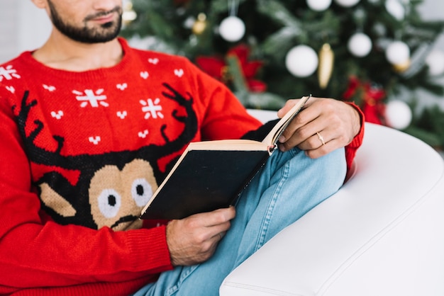 Free photo man holding book on sofa