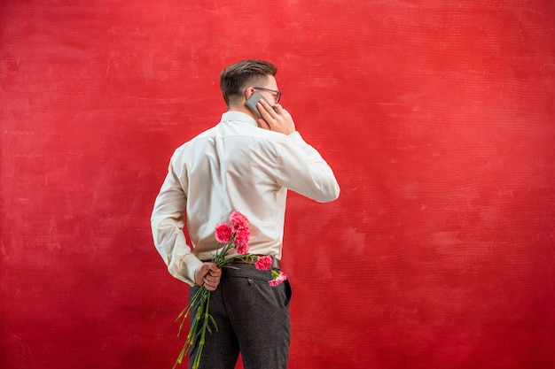 背中の後ろにカーネーションの花束を持って男