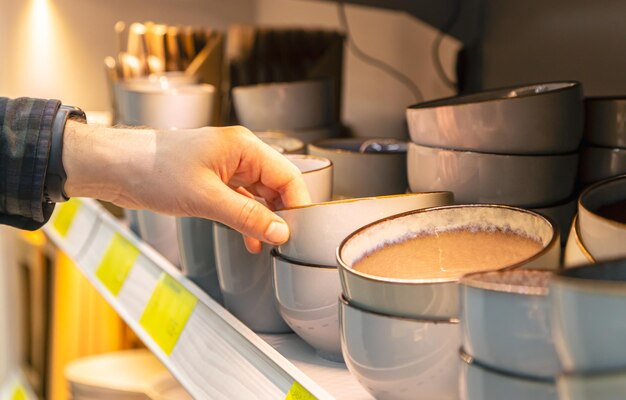 Free photo man holding bowl from a shelf in homeware store