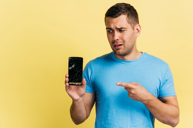 Мужчина держит сломанный телефон
