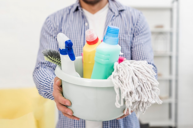 Free photo man holding bucket with cleaning products