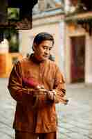 Free photo man holding bundle of incense at the temple