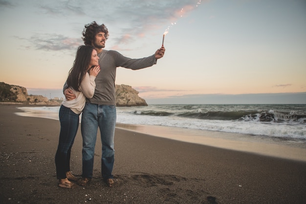 Foto gratuita l'uomo in possesso di un razzo che brucia mentre i suoi sorrisi sposa