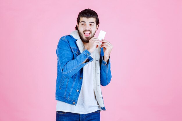 Free photo man holding a business card and looks confused