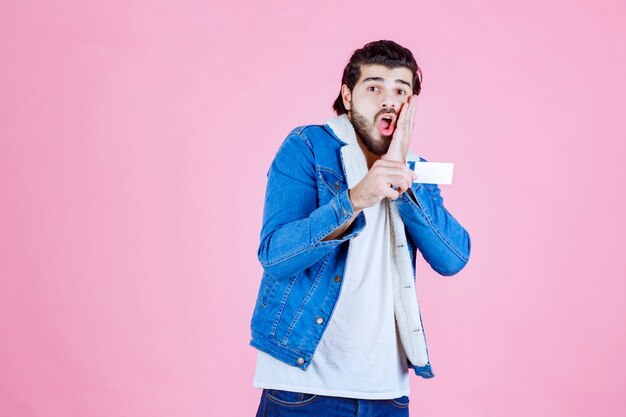 Man holding a business card and looks confused