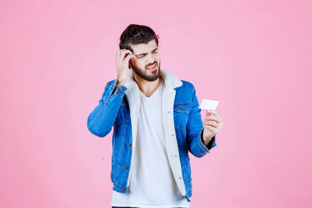 Free photo man holding a business card and looks confused