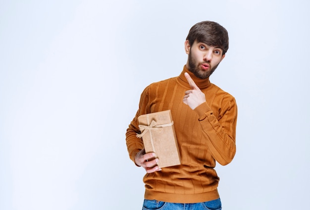 Man holding a cardboard gift box and pointing something in the upside.