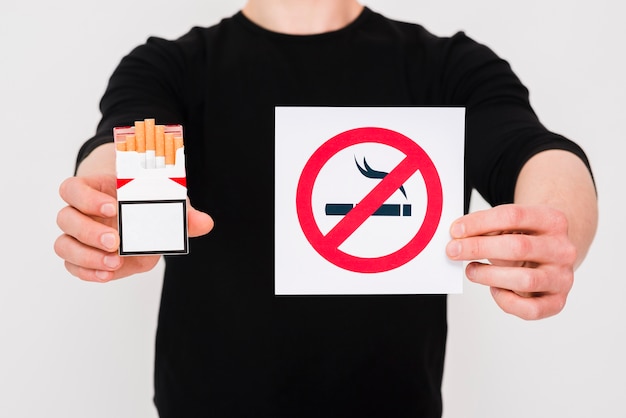 Man holding cigarettes packet and no smoking sign over white background