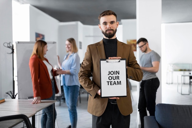 Man holding a clipboard at work with join our team message