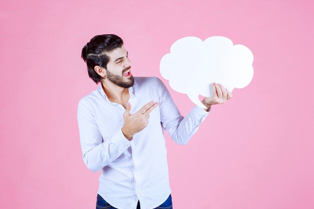 Man holding a cloud shape ideaboard and pointing at it. 