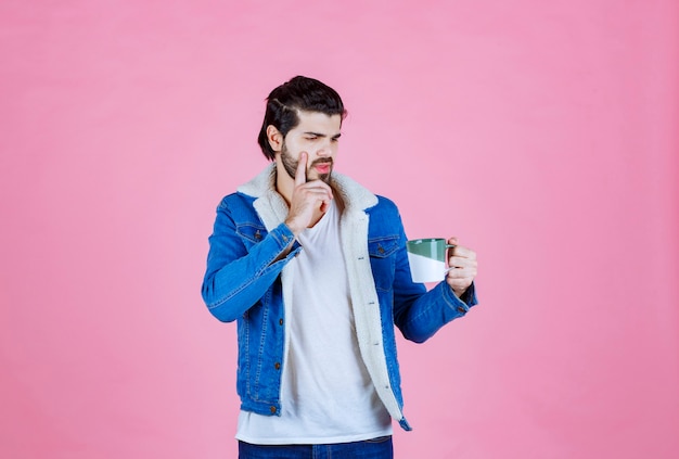 Man holding a coffee cup and looks thoughtful. 