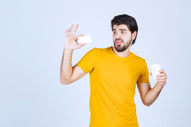 Man holding a coffee cup and presenting his business card.