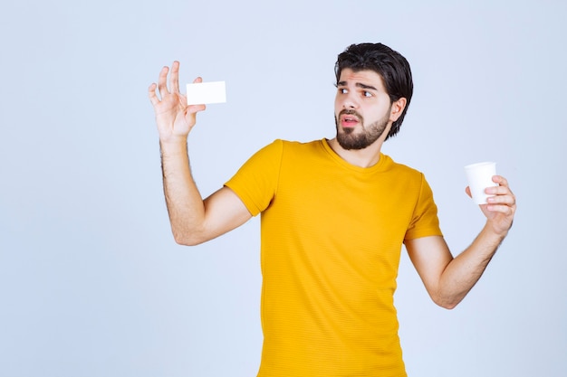 Man holding a coffee cup and presenting his business card.