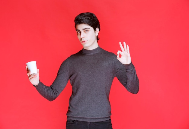 Man holding a coffee cup and showing positive sign