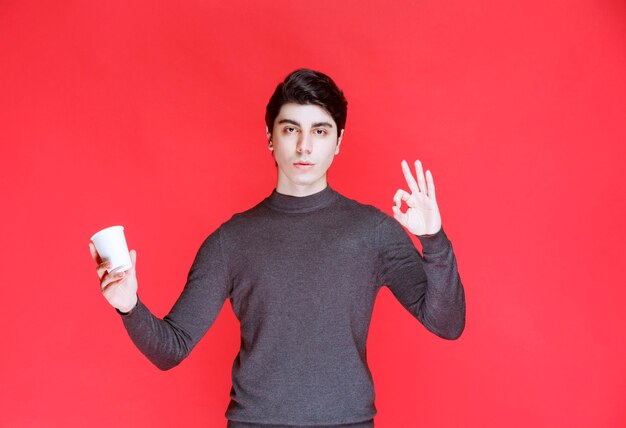 Man holding a coffee cup and showing positive sign