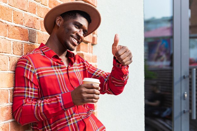 Man holding a coffee and doing the thumbs up gesture