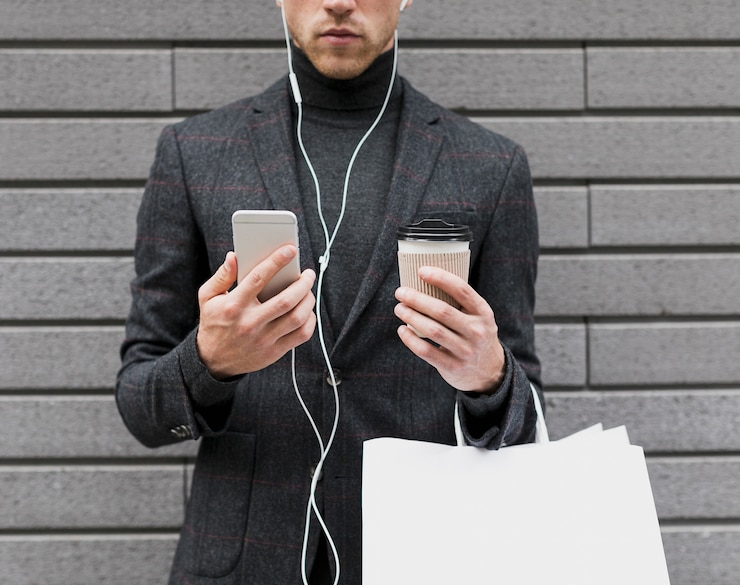 Free Photo man holding coffee and smartphone in his hands