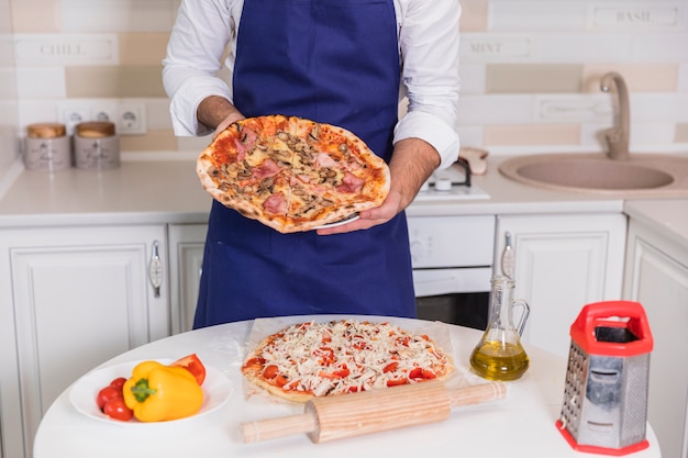 Бесплатное фото Мужчина держит приготовленную пиццу в руках