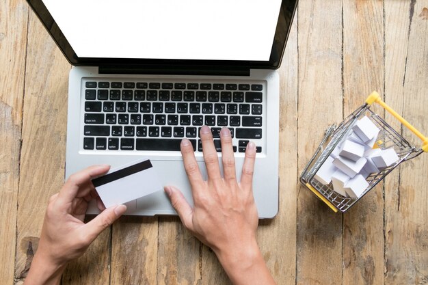 Man holding credit card in hand and entering security code using laptop keyboard