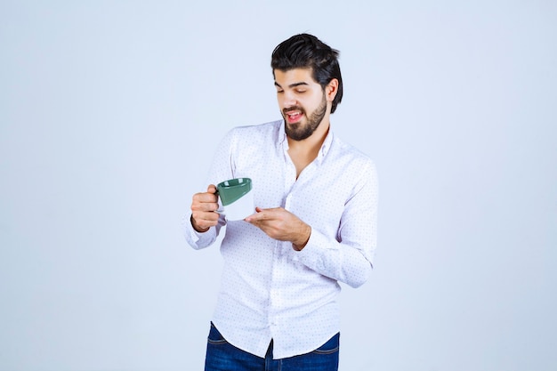 Man holding a cup of drink and feeling satisfied