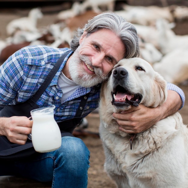 Free photo man holding cup of goat milk while playing with dog