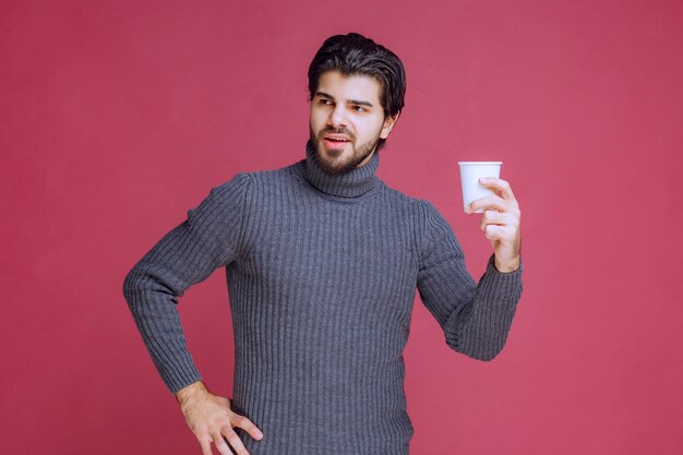 Man holding a disposable coffee cup in the hand and feels positive.