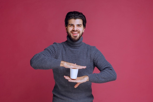 Free photo man holding a disposable coffee cup in the hand and feels positive.