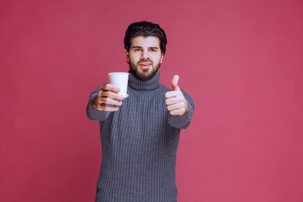 Man holding a disposable coffee cup and makes enjoyment sign.